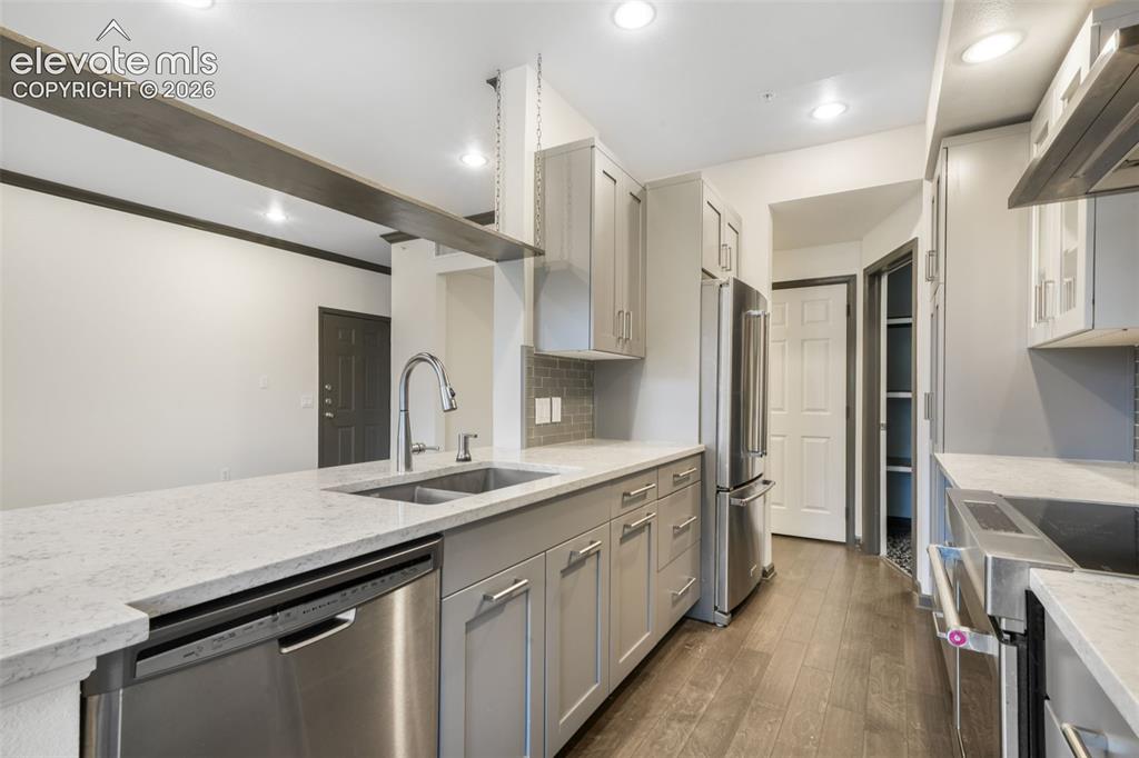 Image 17 of 50: Kitchen featuring light-gray shaker-style cabinetry, quartz countertops, st