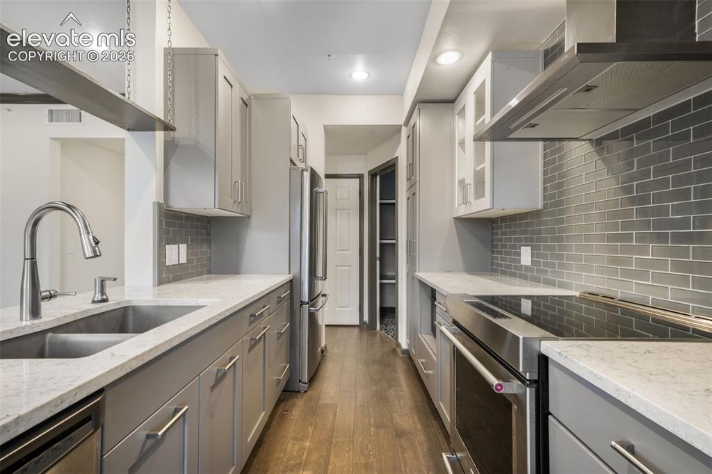 Image 19 of 50: Galley kitchen featuring light grey shaker cabinetry, stone-finish countert