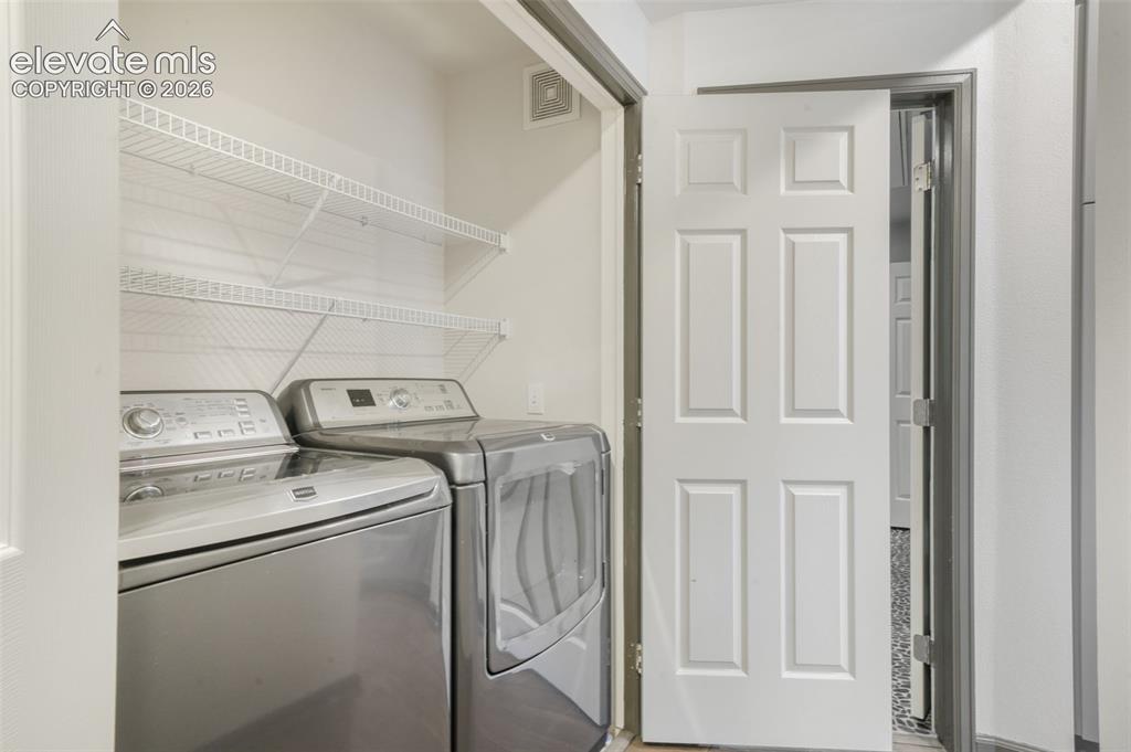 Image 25 of 50: Laundry area featuring built-in wire shelving and a six-panel interior door