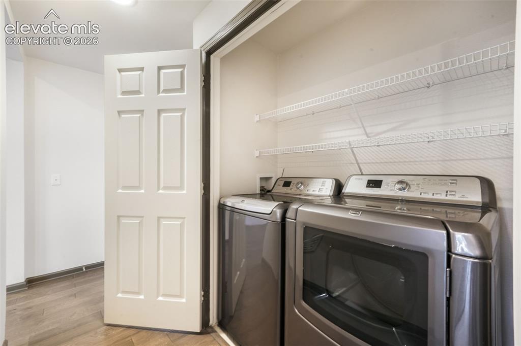 Image 26 of 50: Laundry area featuring wood-finish flooring, a six-panel door, and integrat