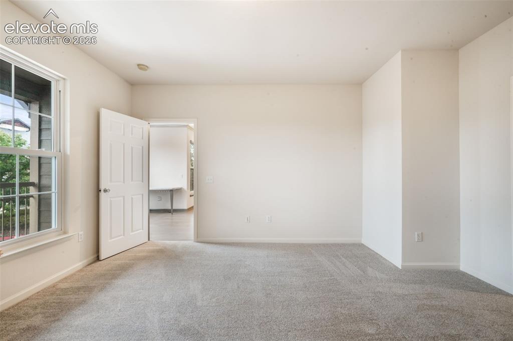 Image 31 of 50: Neutral wall tones, wall-to-wall carpeting, and a six-panel interior door