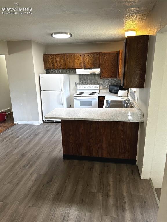 Image 4 of 14: Kitchen featuring wood-finish cabinetry, white appliances, dual basin sink,