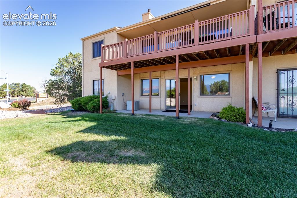 Image 11 of 29: Ground-level patio with sliding glass door access, an upper-level balcony,