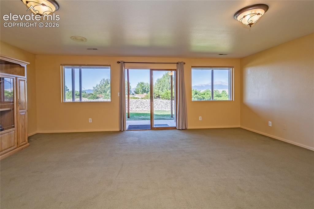 Image 24 of 29: Walk out basement living with sliding glass, concrete patio, amazing views.