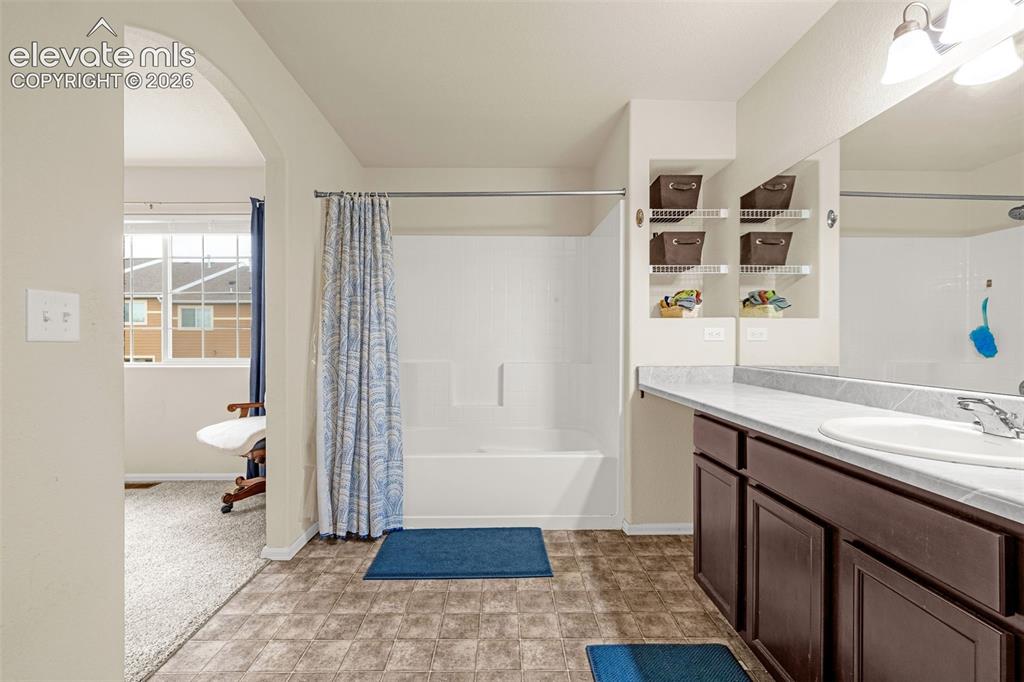 Image 14 of 32: Brown wood-finish vanity with a white countertop and integrated sink