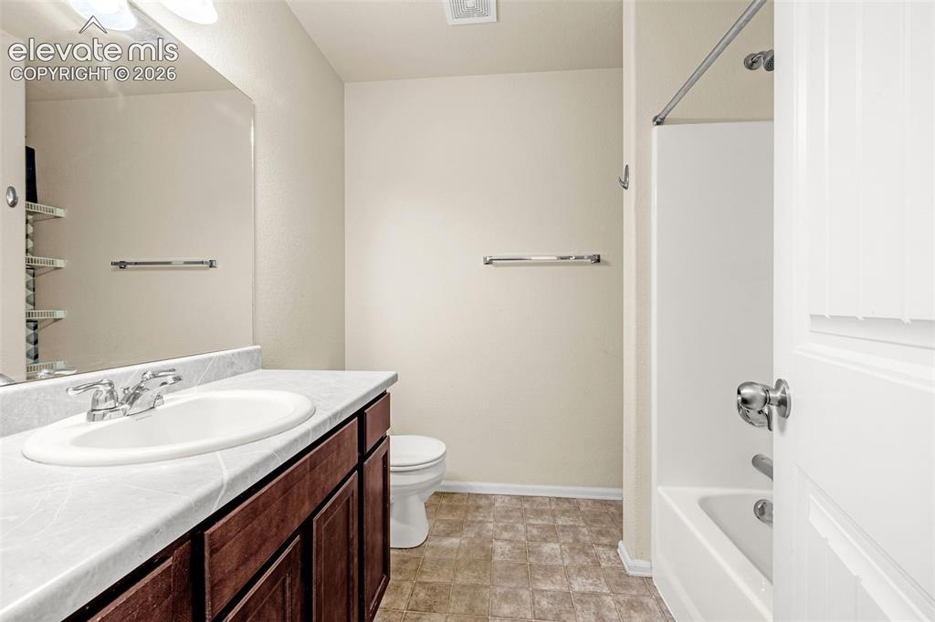 Image 17 of 32: Warm-toned wood-finish vanity with an integrated sink and chrome faucet, se