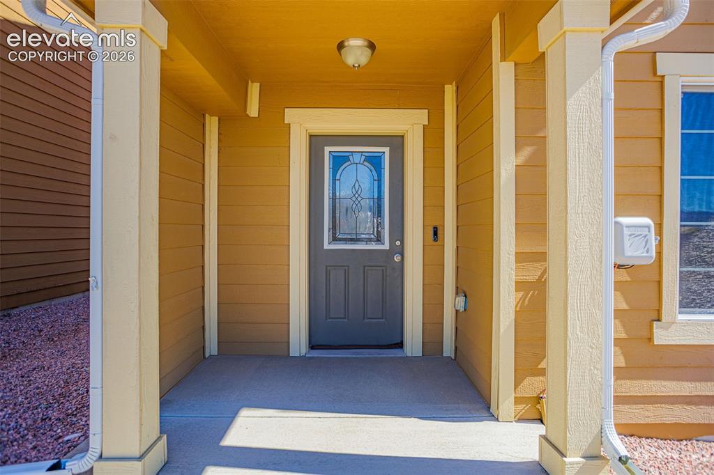 Image 3 of 32: Covered entry porch featuring a paneled door with decorative glass inlay, r
