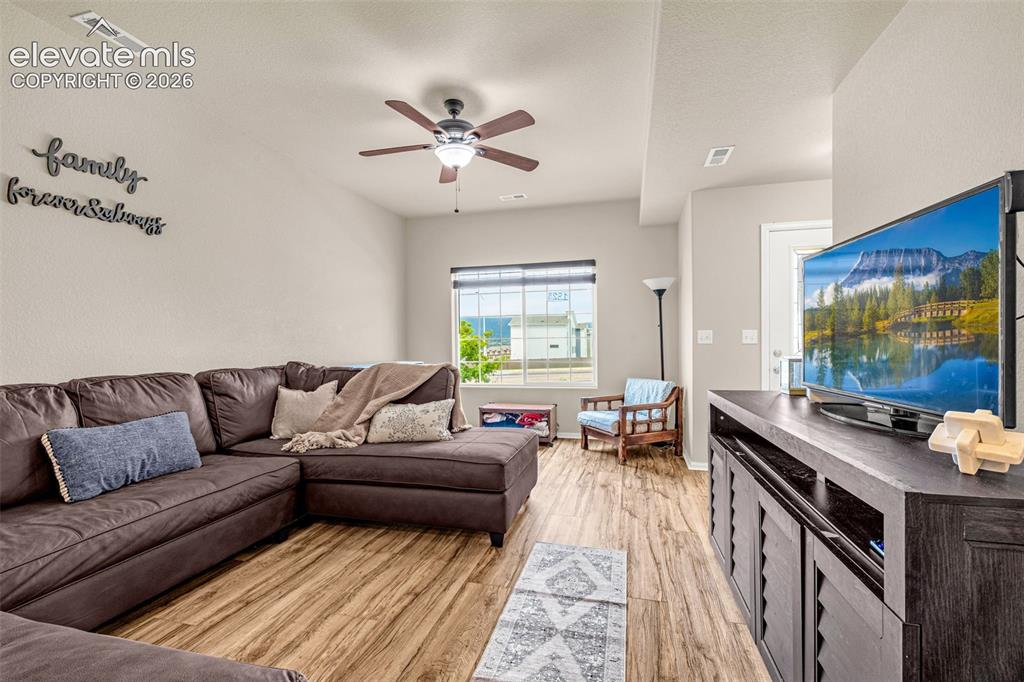 Image 6 of 32: Wood-finish flooring throughout, complemented by a ceiling fan with integra