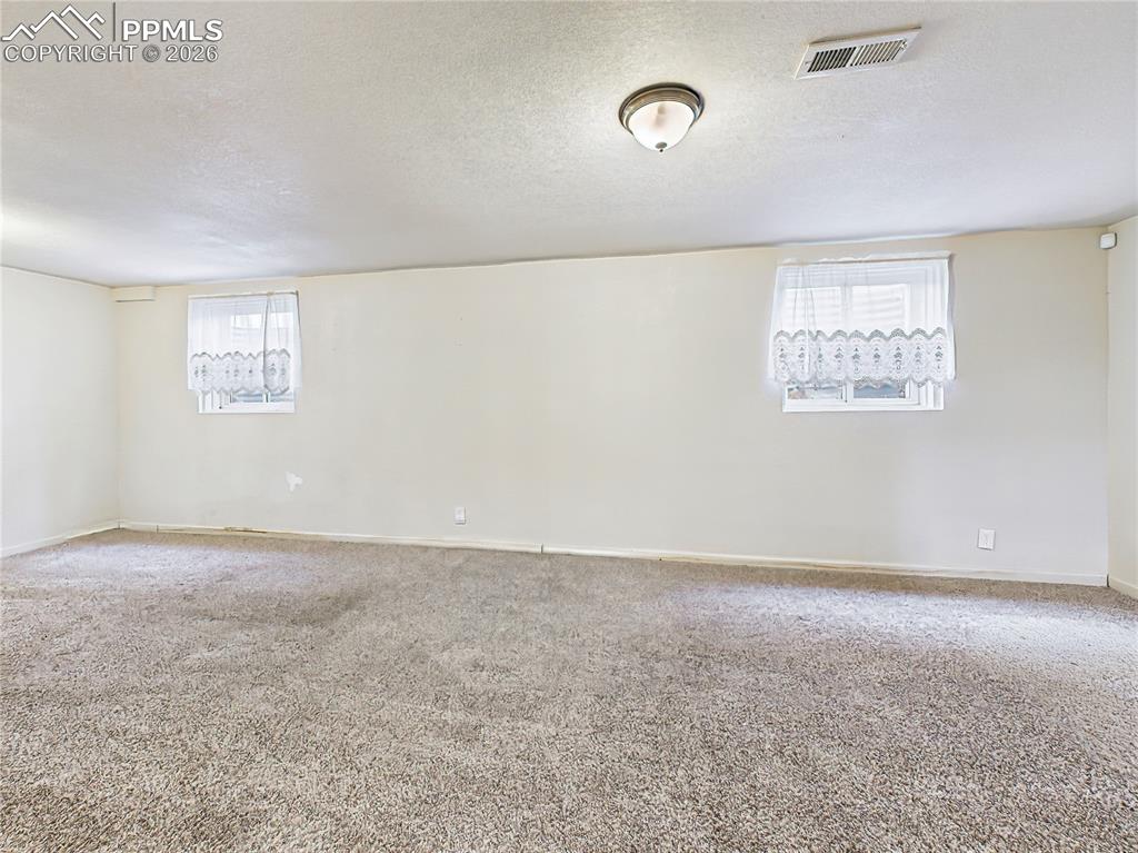 Image 28 of 50: A large multipurpose area with wall-to-wall carpet and recessed layout, off