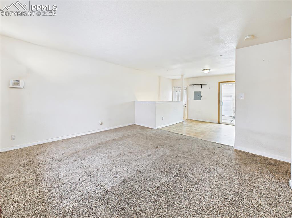 Image 3 of 50: Bright and welcoming main living space with large window, plush carpeting, 