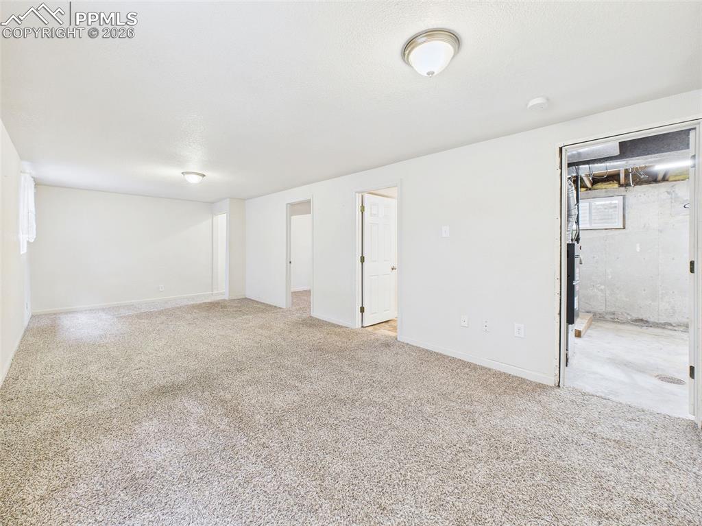 Image 30 of 50: Spacious basement bonus room with dual windows and soft carpet, ideal for u