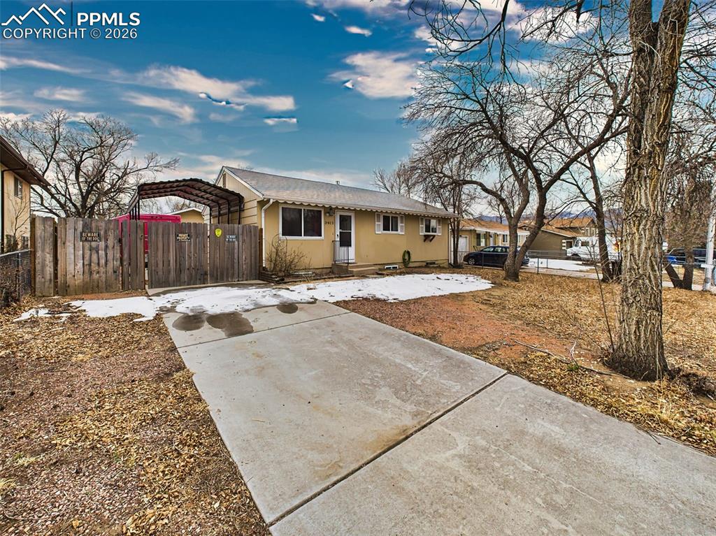 Image 41 of 50: A concrete driveway leads to a covered carport and private fenced yard—an i