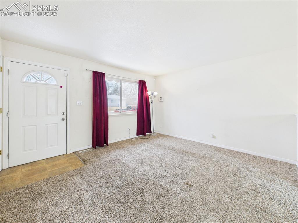 Image 9 of 50: This spacious front living area features plush carpeting and is flooded wit