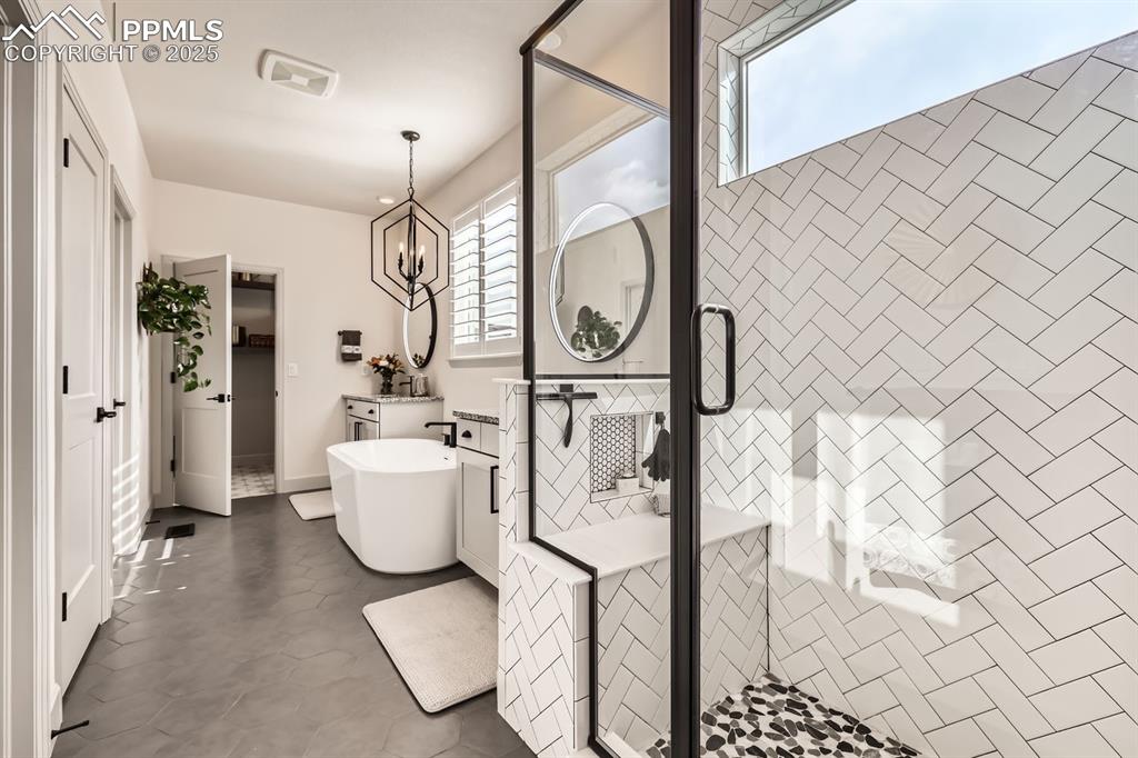 Image 13 of 28: Bathroom featuring a chandelier and shower with separate bathtub