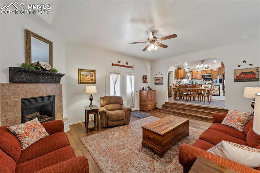 Image 4 of 9: Living area with wood finished floors, arched walkways, a fireplace, and a 