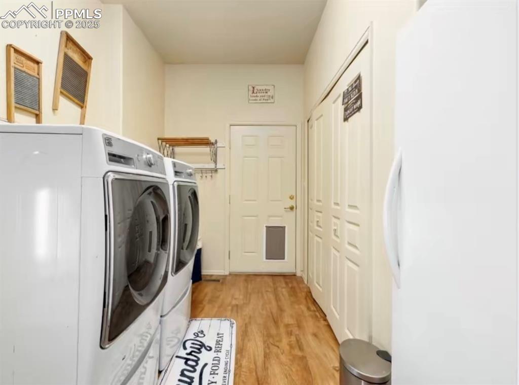 Image 8 of 9: Laundry area with washing machine and dryer and light wood finished floors