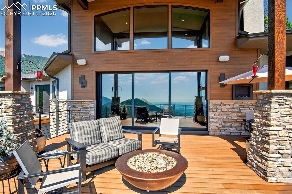 Image 16 of 50: Covered walk out deck from the living room with built in fire pit 