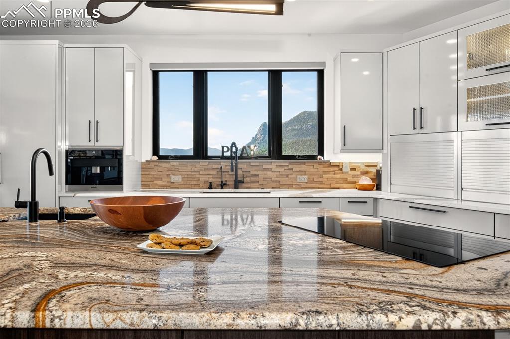 Image 26 of 50: Custom carressed granite countertops with cook top and a black sandstone si