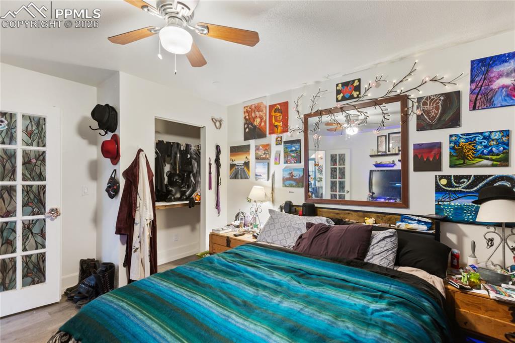 Image 10 of 34: The main bedroom has a ceiling fan, wood-finished floors, and French doors!