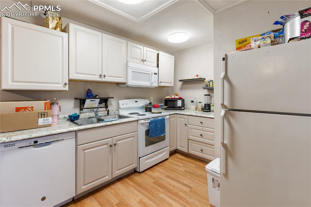 Image 24 of 34: The kitchen has white appliances, light countertops, light wood-style floor