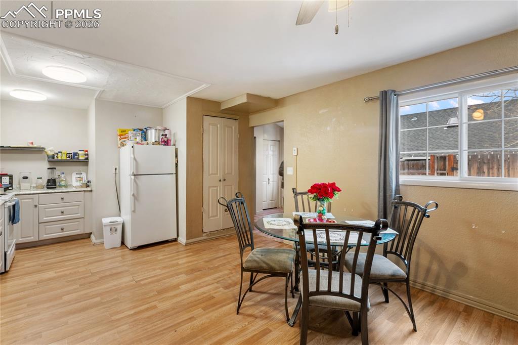 Image 26 of 34: The dining room has light wood-style flooring and a ceiling fan overlooking