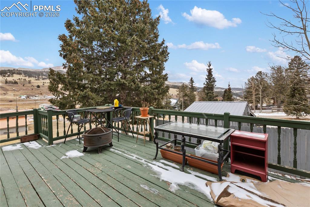 Image 3 of 34: A spacious deck overlooking a scenic mountain valley with tall mature trees