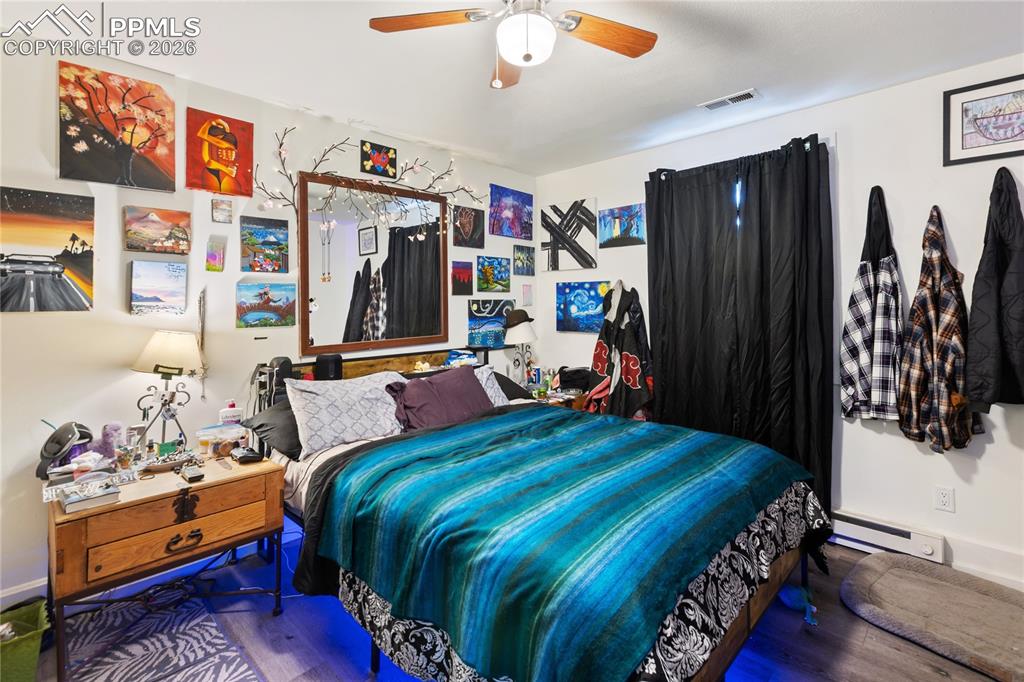 Image 9 of 34: The main bedroom with a baseboard heating unit, wood finished floors, and c