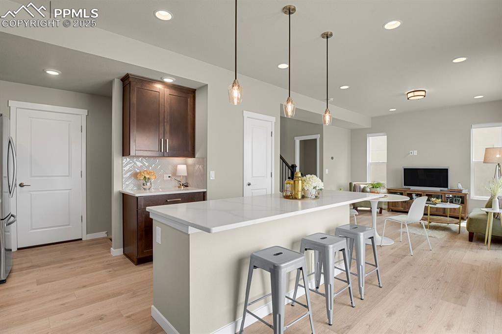 Image 11 of 32: Kitchen island with pendant lighting and quartz countertops and custom tile