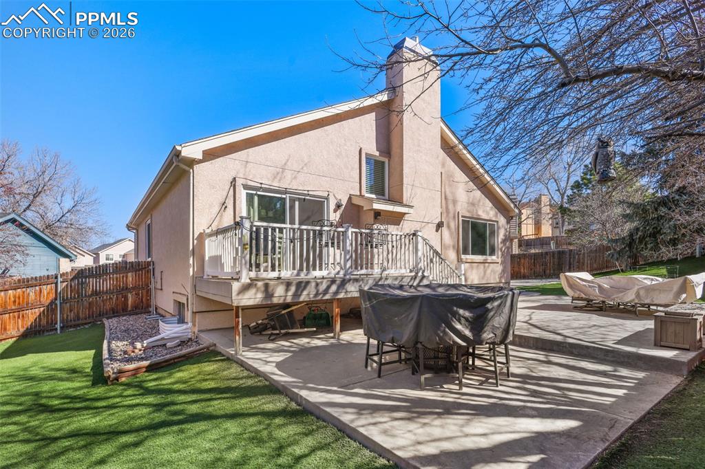 Image 23 of 29: Back of house featuring Astroturf, deck and private backyard