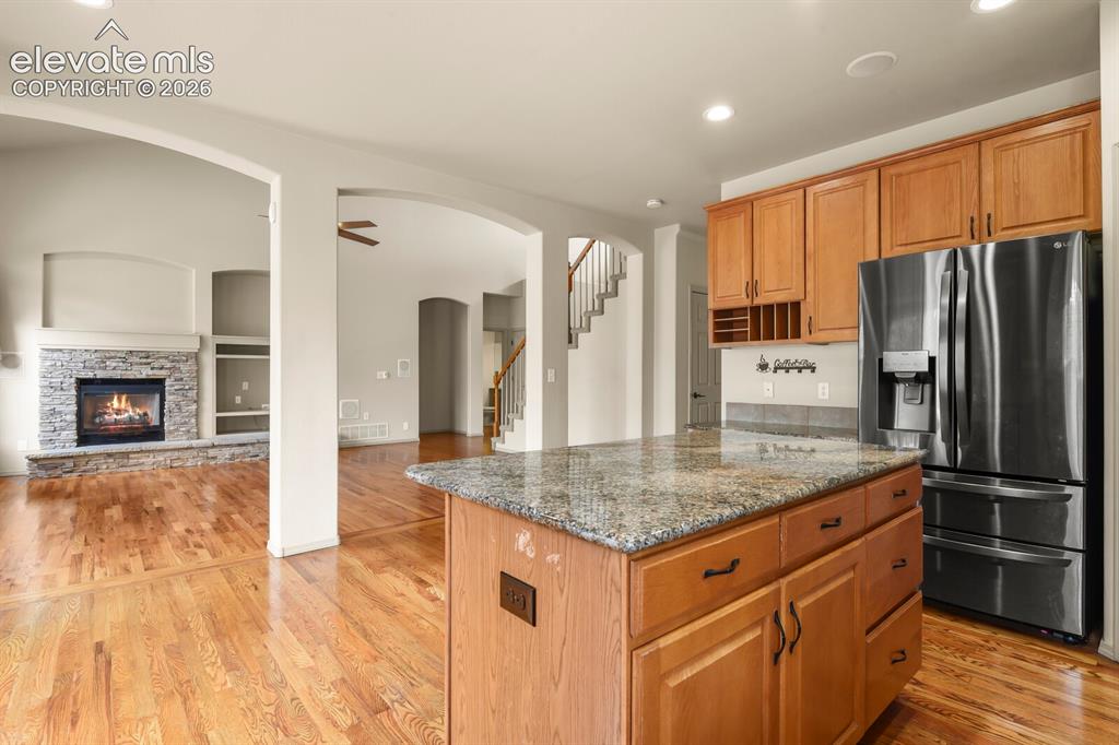 Image 10 of 50: Kitchen island with granite countertop, wood cabinetry, and stainless steel