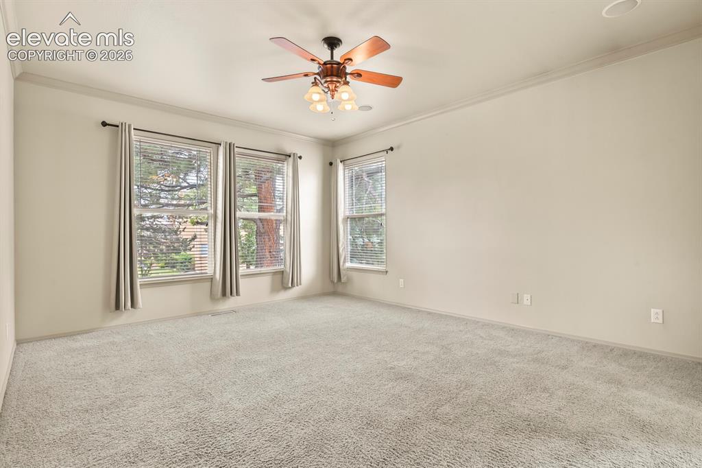 Image 17 of 50: Carpeted room featuring multiple windows with blinds, a ceiling fan with in