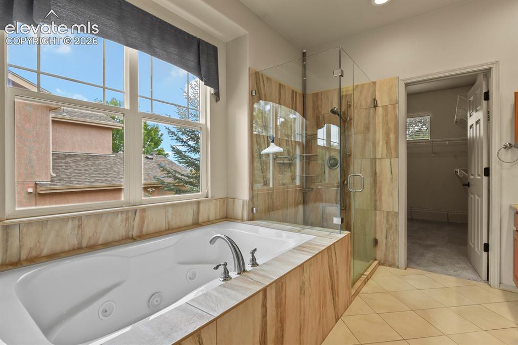 Image 20 of 50: Spacious bathroom featuring a built-in jetted tub with tile surround, a lar