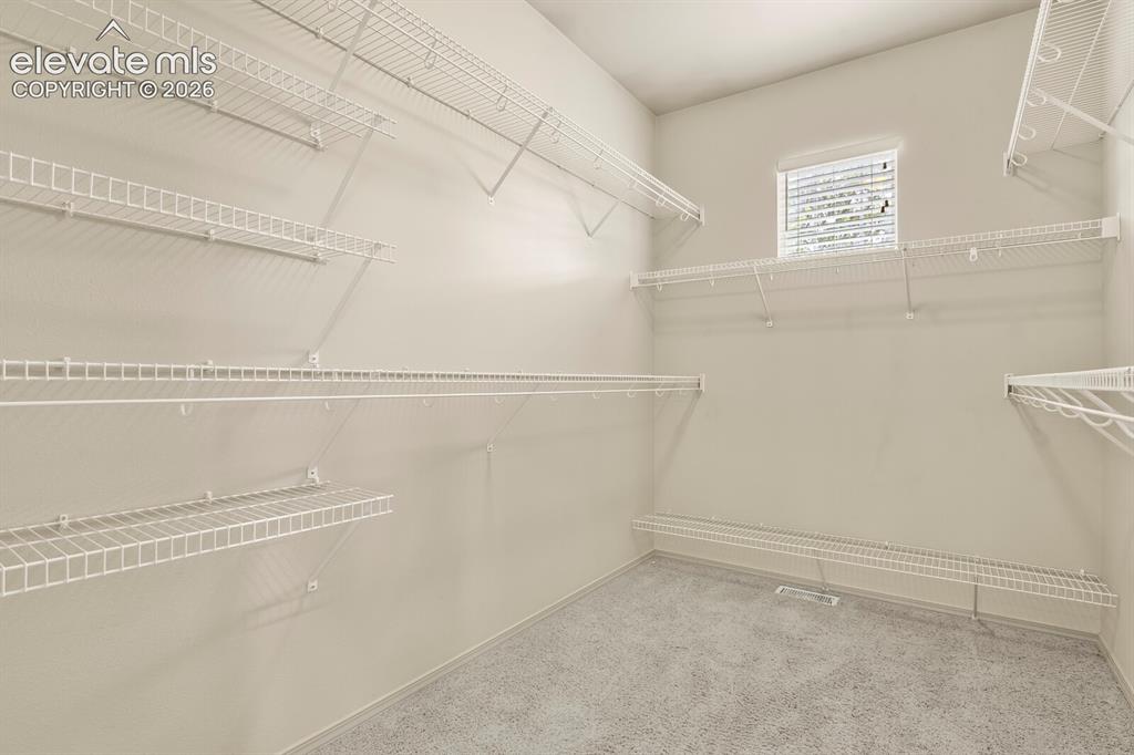 Image 21 of 50: Primary Bedroom Closet is a true Walk in with Carpet, featuring multiple wi