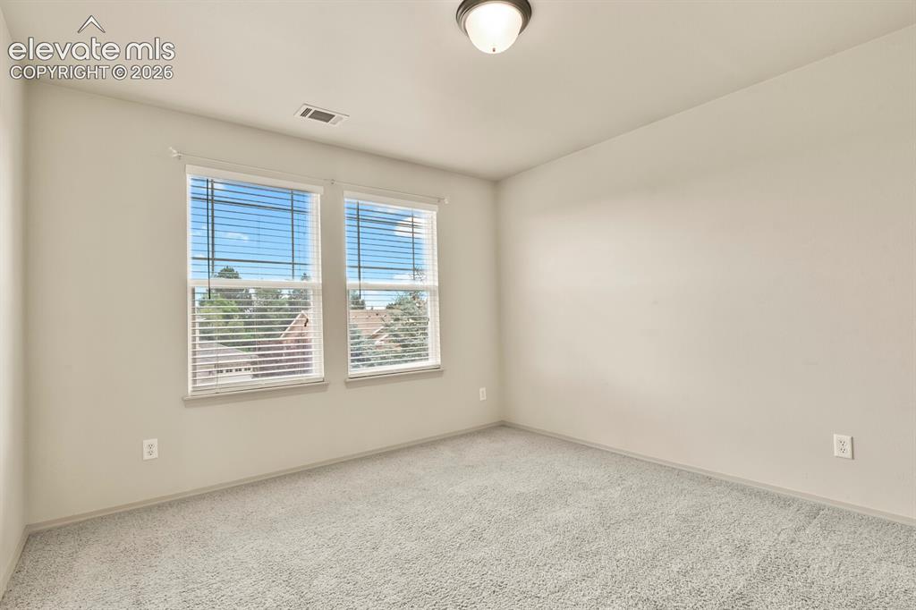 Image 23 of 50: Carpeted interior space featuring two windows with blinds, a ceiling-mounte