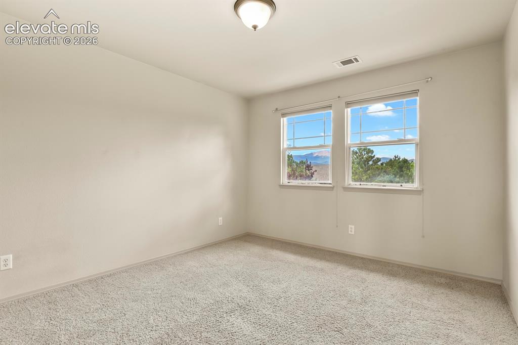 Image 26 of 50: #2 upper Bedroom with light carpet, two windows with mountain scenery