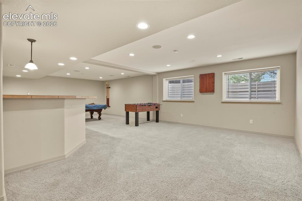 Image 28 of 50: Lower Family room Open recreational space featuring Foos Ball, Built in Dar
