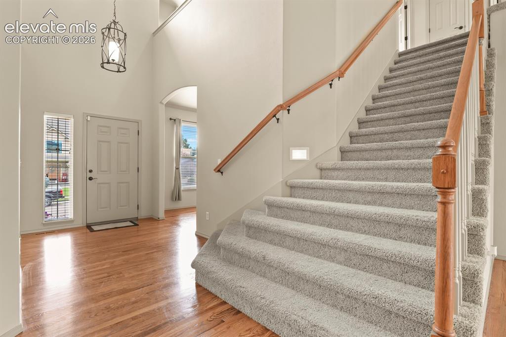 Image 5 of 50: Entryway featuring wood-finish flooring, a carpeted staircase with wood han