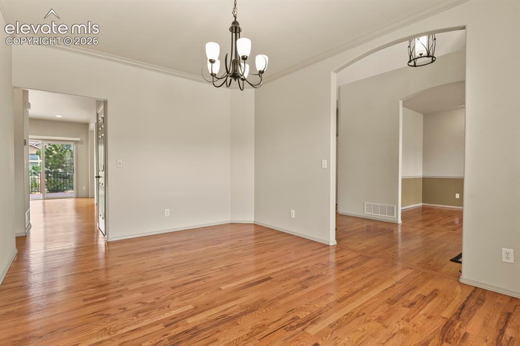 Image 7 of 50: Hardwood flooring throughout, featuring crown molding, a decorative chandel