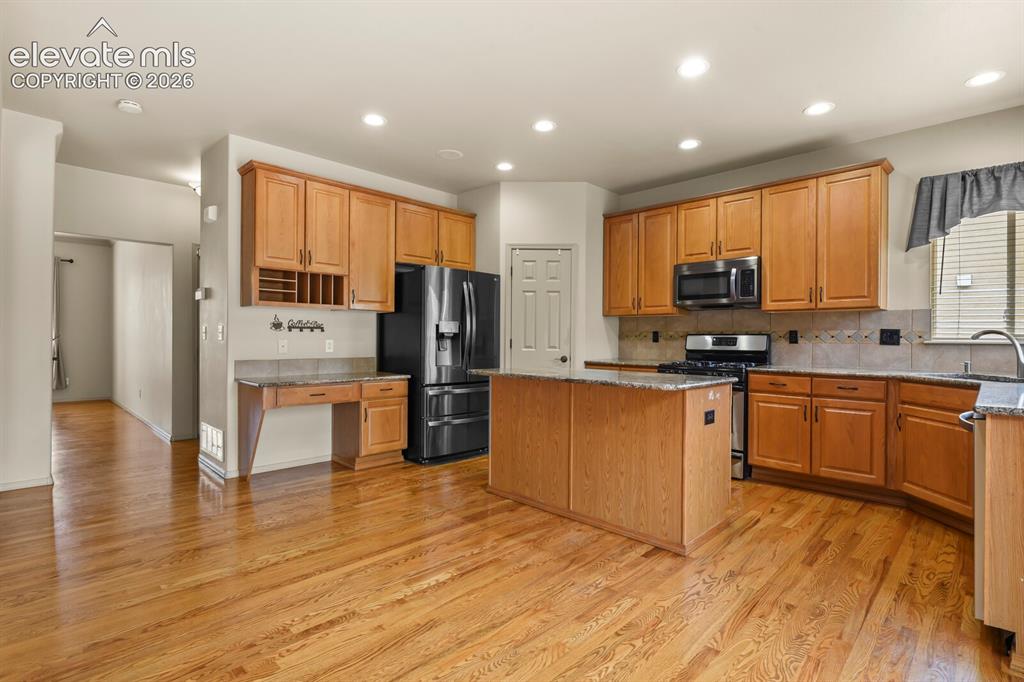 Image 9 of 50: Kitchen featuring wood-finish flooring, recessed lighting, and a central is