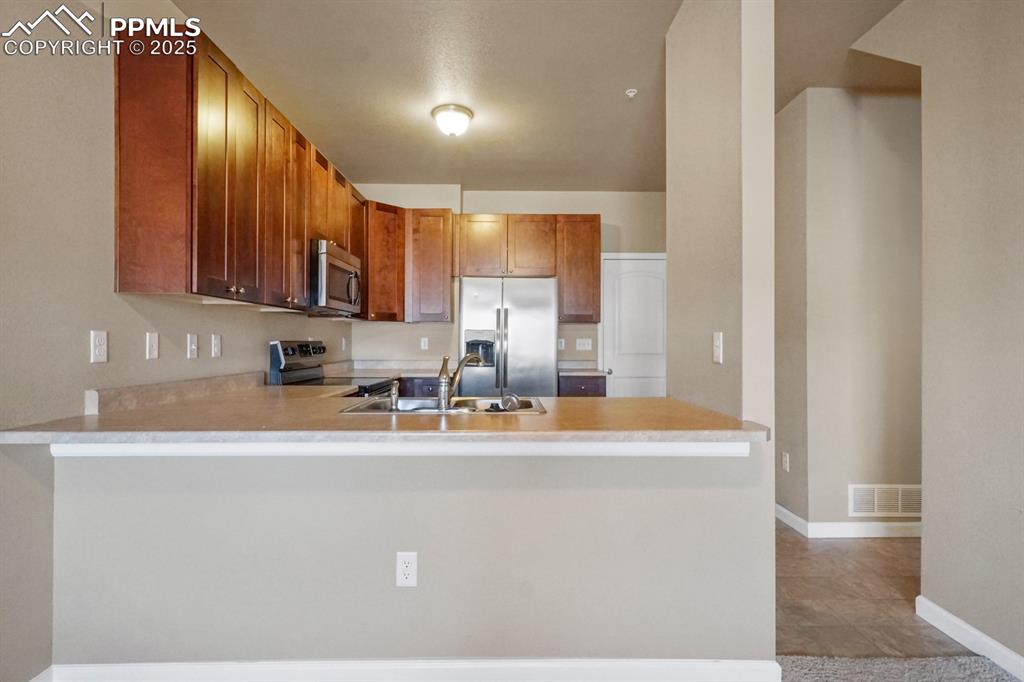 Image 4 of 18: Kitchen with appliances with stainless steel finishes, a peninsula, light c