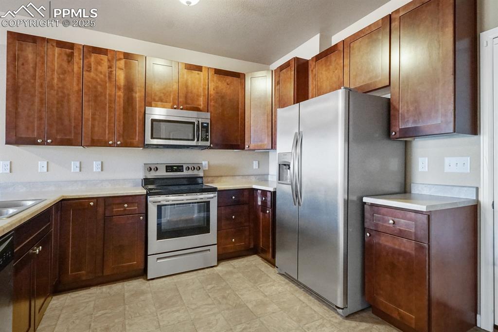 Image 5 of 18: Kitchen with stainless steel appliances, light countertops, and light floor