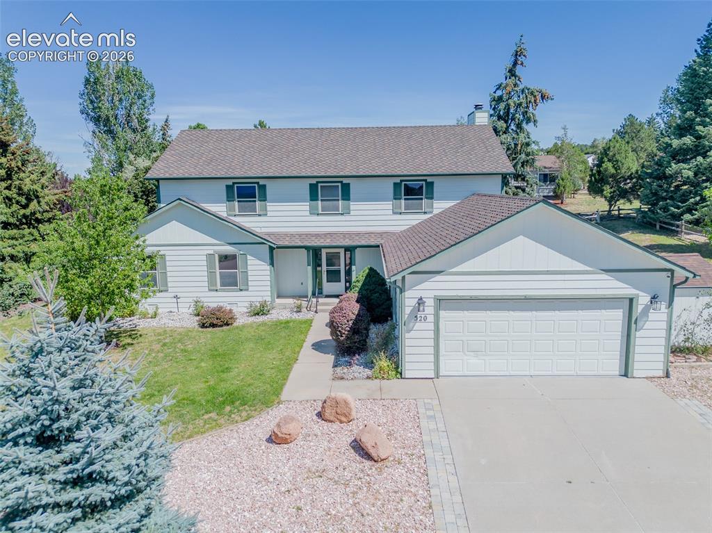 Caption: Two-story residence featuring light-colored siding with dark trim, an attached two-car garage, and a