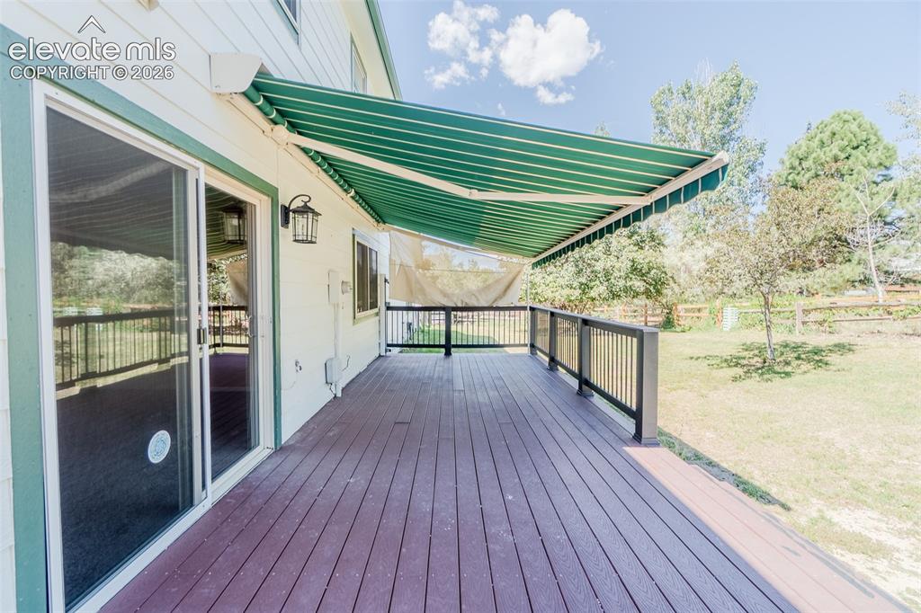 Image 10 of 47: Expansive outdoor deck with wood-finish flooring, black railings, and a gre