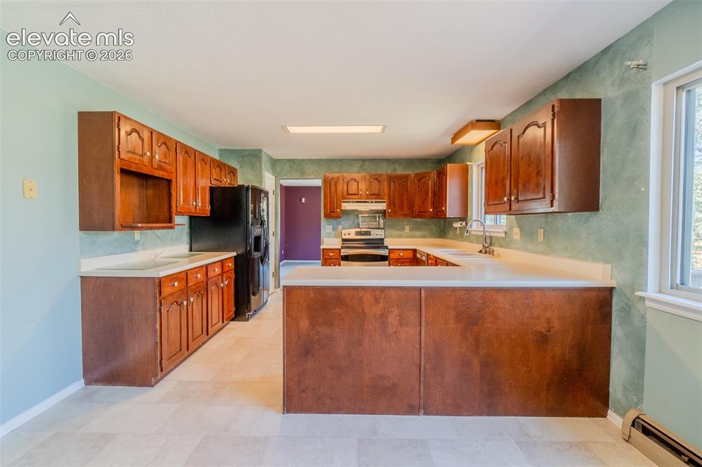 Image 12 of 47: Kitchen featuring wood cabinetry, light-toned countertops, tile flooring, a