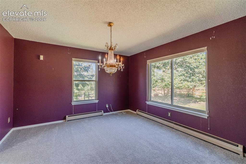 Image 22 of 47: Room featuring two windows, carpeted flooring, and a decorative chandelier
