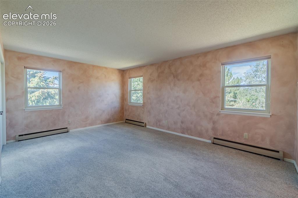 Image 38 of 47: Fourth bedroom upstairs with new carpet and   room featuring textured wall 