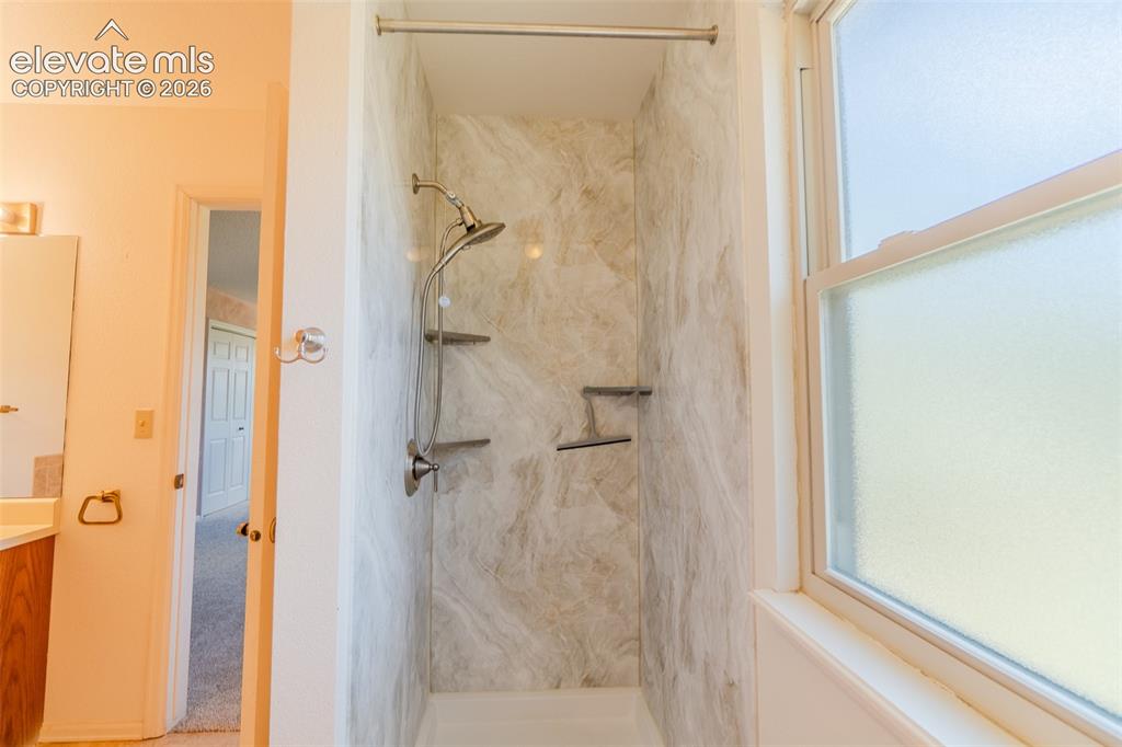 Image 42 of 47: Shower with integrated shelving, handheld shower, and brushed nickel fixtur