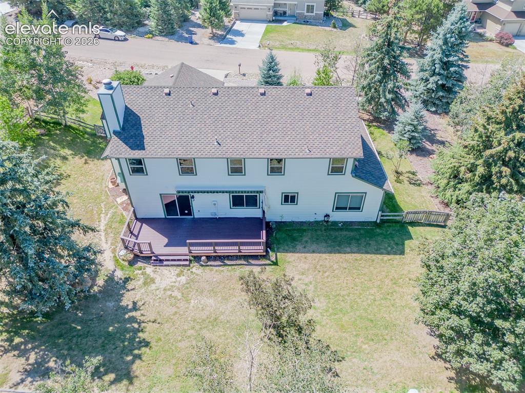 Image 6 of 47: Two-story residence featuring a shingled roof, exterior chimney, and multip