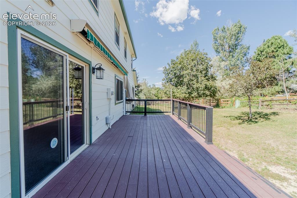 Image 9 of 47: Expansive wood-finish deck with dark railing, featuring a large sliding gla
