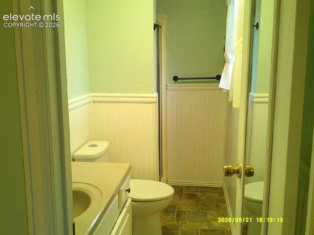 Image 14 of 26: Bathroom featuring wainscoting, a vanity with an integrated sink, and a toi